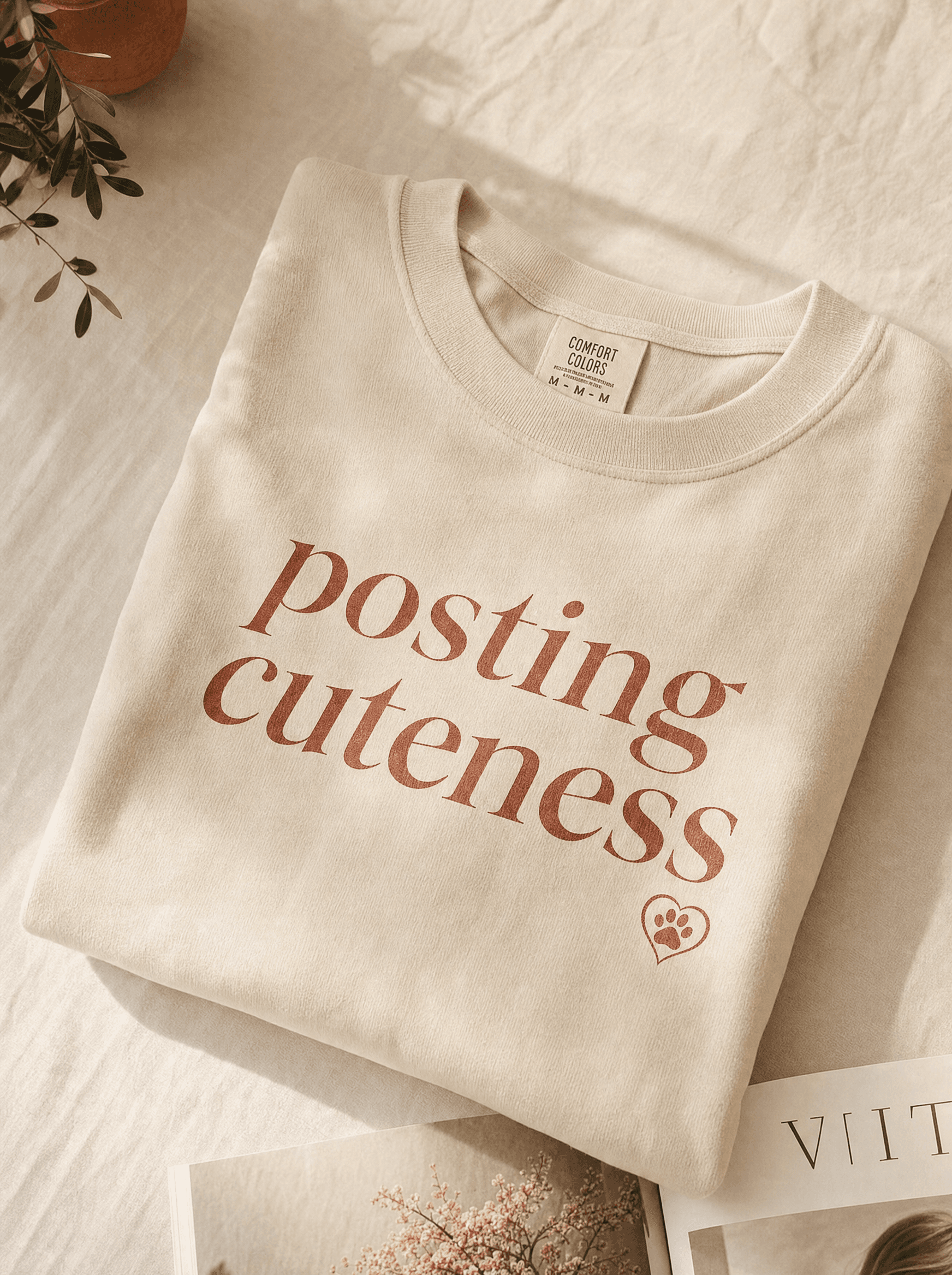 Heavyweight cream tee with 'posting cuteness' italic wordmark and paw-in-heart logo